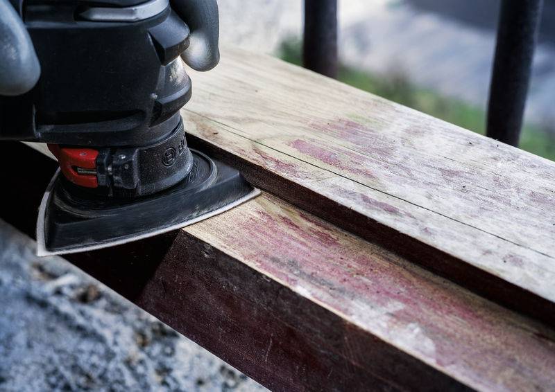 Eine Schleifmaschine bearbeitet ein längliches Holzstück, um die Oberfläche zu glätten.