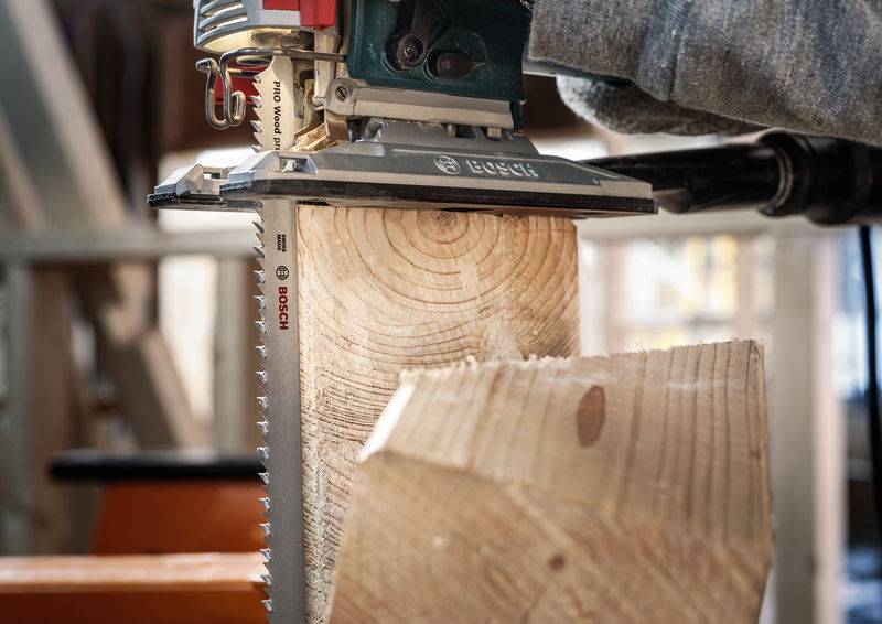 Eine elektrische Säge schneidet präzise durch einen Holzstamm. Sägeblätter und Holzstruktur sind deutlich sichtbar.