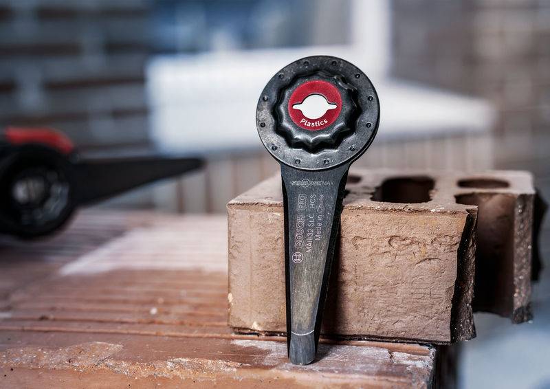 Ein Sandstein mit einem Plastikdorn darauf, der zur Verankerung von Bauteilen dient. Im Hintergrund unscharfe Ziegel.