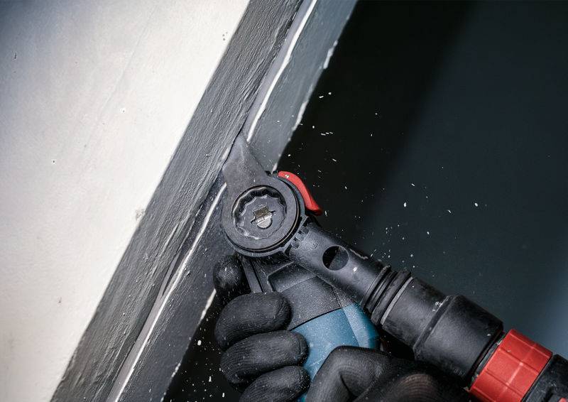 Eine Person reinigt eine Fensterfuge mit einem elektrischen Werkzeug. Es entstehen kleine Materialspäne.