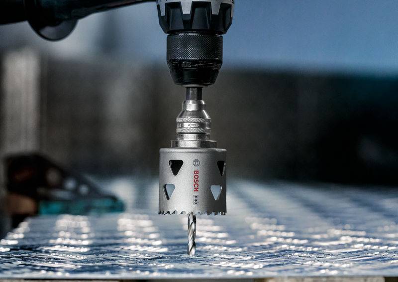 Nahaufnahme eines Bohrers, der eine Metallscheibe durchbohrt. Der Bohrer wird von einem mechanischen Arm gehalten.