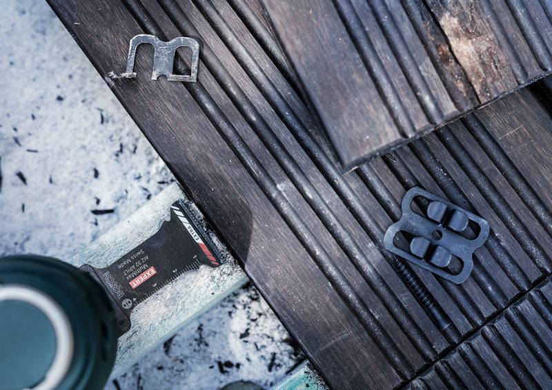 Nahaufnahme von Holzbrettern auf einer Werkbank mit Metallklammern und Werkzeug.