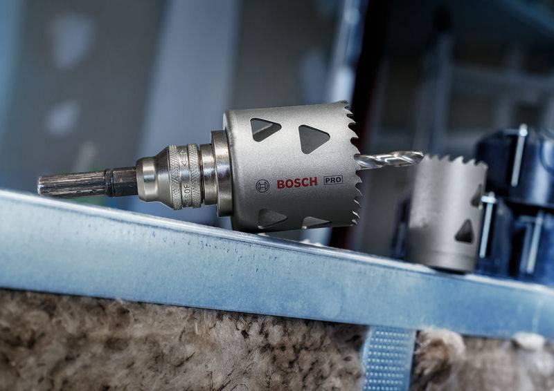 'BOSCH Pro' Lochsäge mit zahnförmiger Sägekrone und Bohreraufsatz, montiert auf Metallträger in einer Werkstattumgebung.
