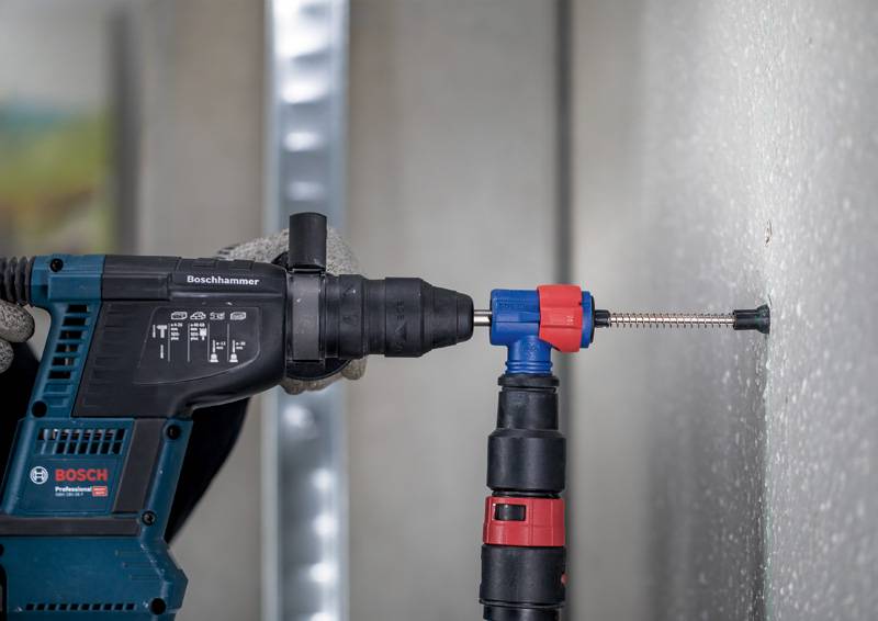 Eine Bohrmaschine wird verwendet, um in eine Betonwand zu bohren. Die Maschine ist blau mit schwarzen und roten Teilen.