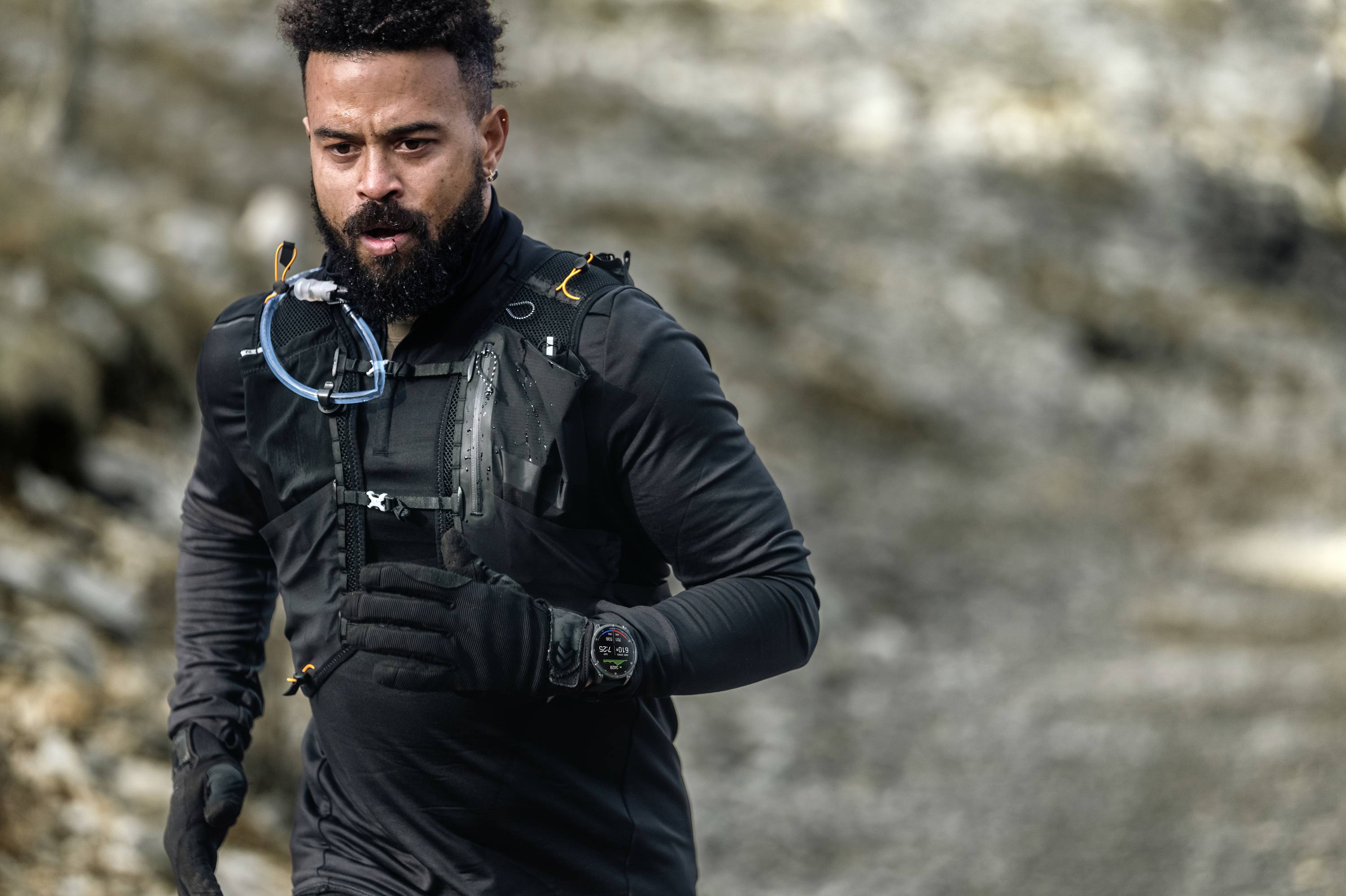 Mann joggt auf einem felsigen Weg, trägt schwarze Sportkleidung und Uhr.