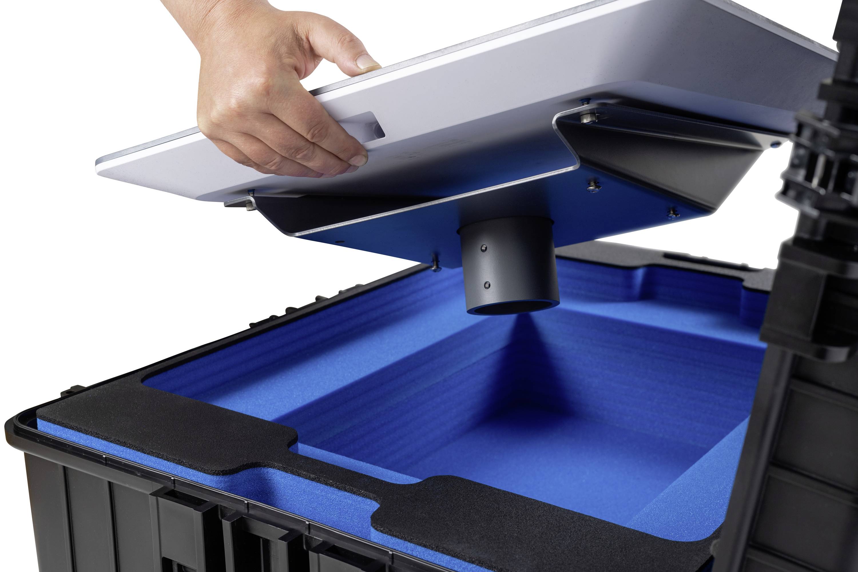 Eine Hand hebt einen weißen Deckel von einer schwarzen Kiste mit blauer Innenverkleidung ab.