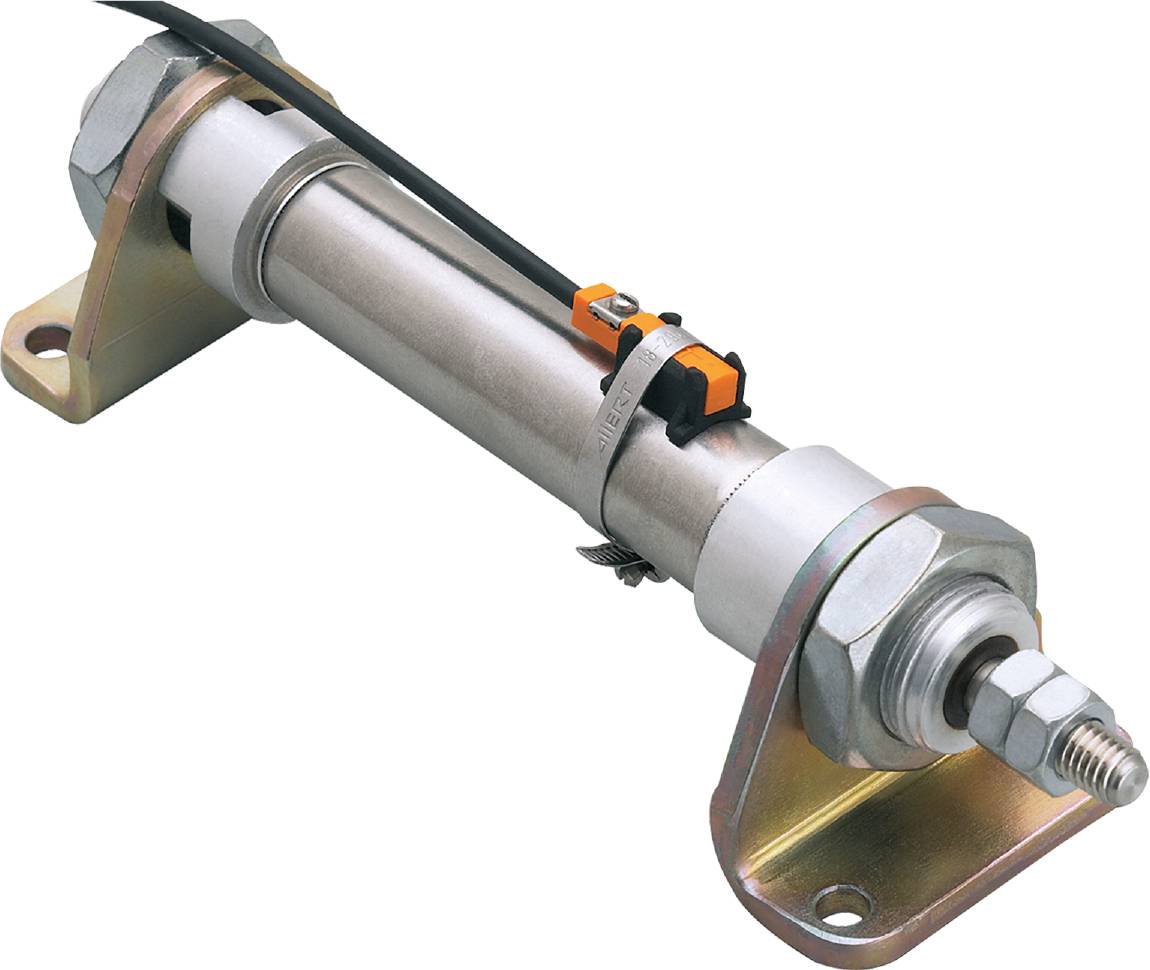 Ein Hydraulikzylinder mit metallischem Gehäuse und Steckverbindungen, montiert auf einer Halterung vor schwarzem Hintergrund.