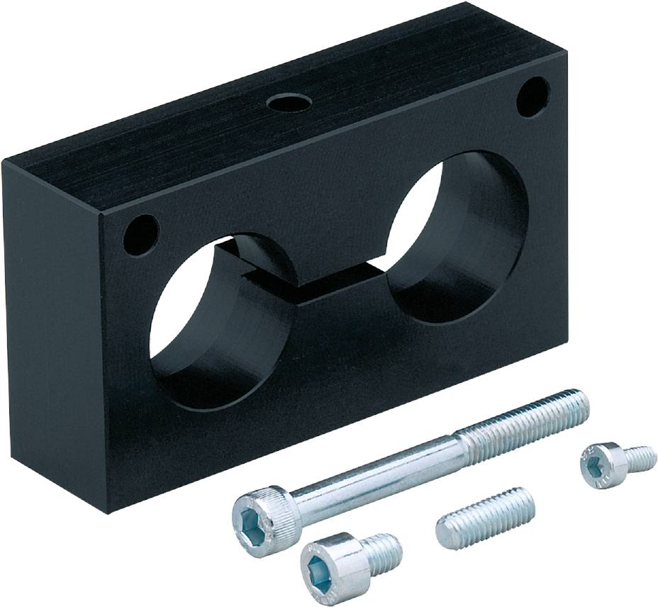 Ein rechteckiger schwarzer Metallblock mit zwei runden Öffnungen und drei Schrauben unterschiedlicher Länge daneben.