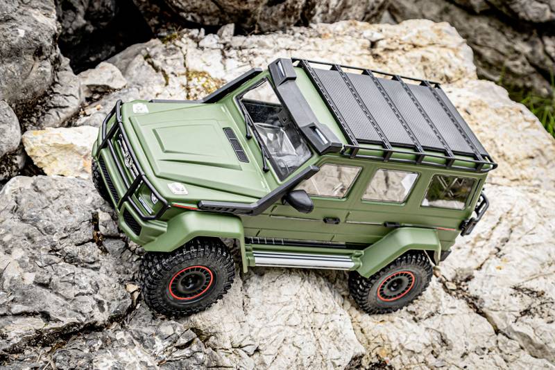 Ein grünes ferngesteuertes Geländewagen-Modell steht auf einem felsigen Untergrund und zeigt Detailtreue und Robustheit.