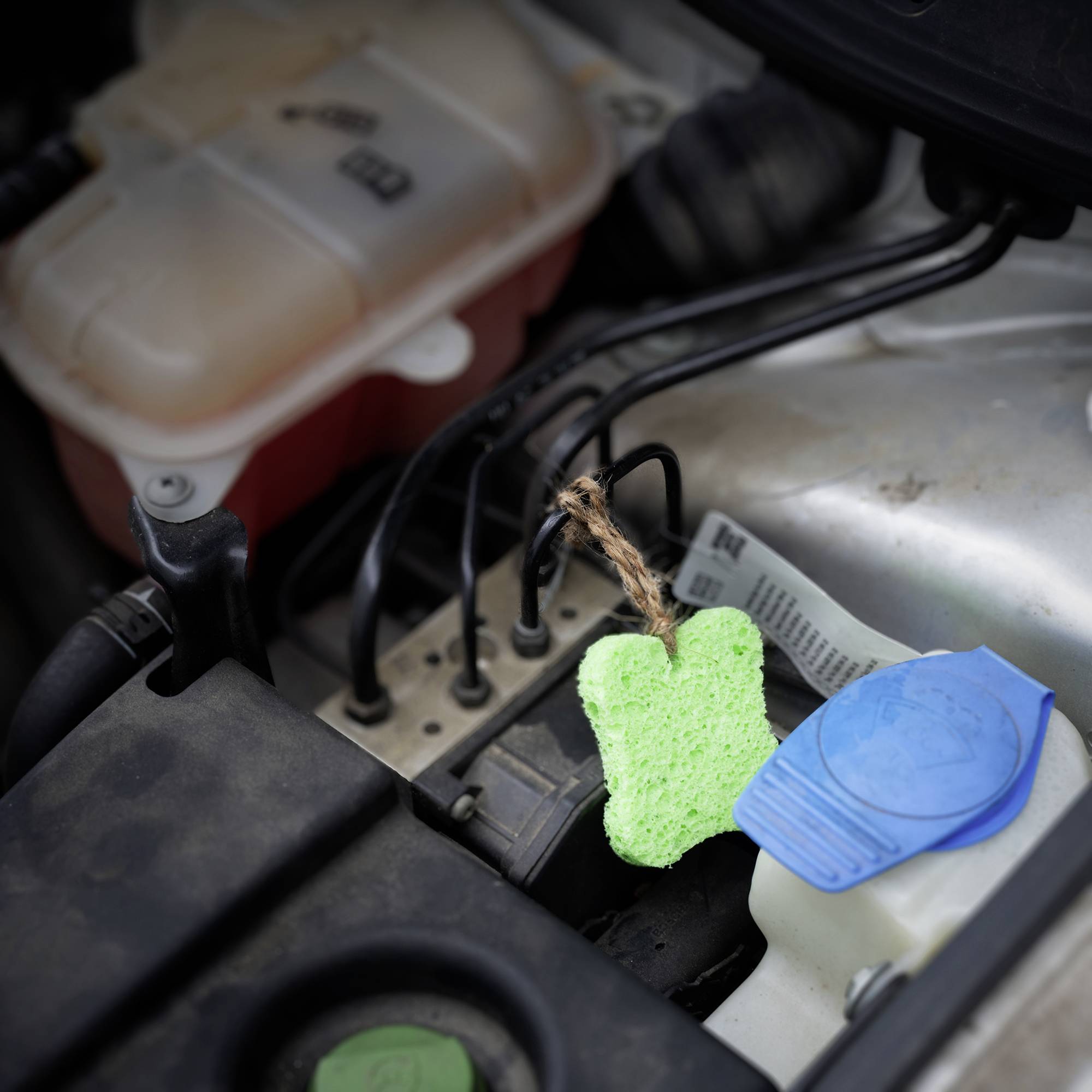 Grüner und blauer Kreidestift auf einer Autobatterie unter der Motorhaube.