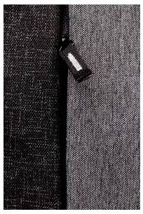 Nahaufnahme einer dunklen Stoffstruktur mit einem kleinen Etikett, das an einer Naht befestigt ist.