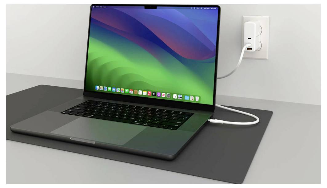 Ein geöffneter Laptop, der auf einem Tisch liegt, ist an eine Steckdose angeschlossen und zeigt einen grünen und blauen Bildschirmschoner.