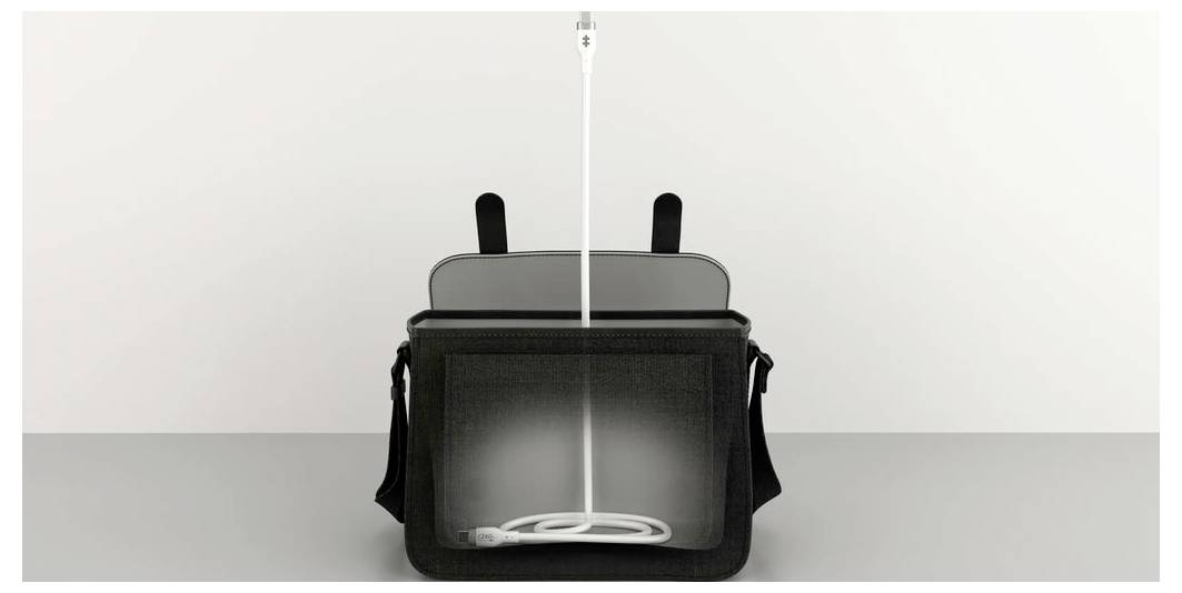 Eine schwarze Umhängetasche auf einem Tisch mit einem offenen Hauptfach; darin ist ein weißes Kabel sichtbar.