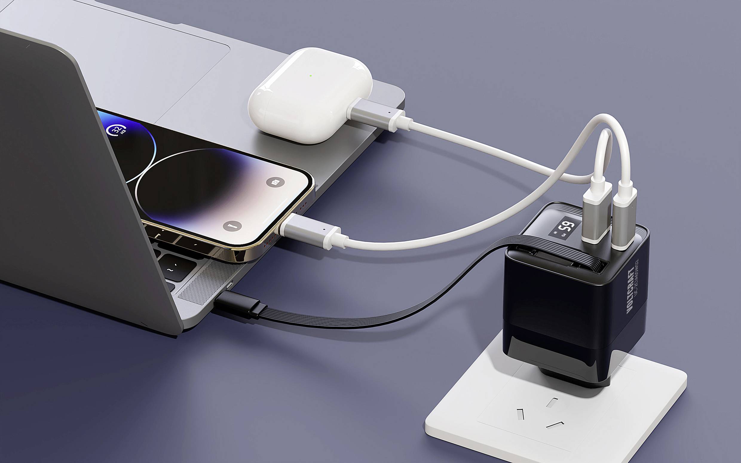 Ein Laptop und ein Smartphone sind an ein Ladegerät angeschlossen. Daneben liegt ein offenes Etui mit kabellosen Kopfhörern.