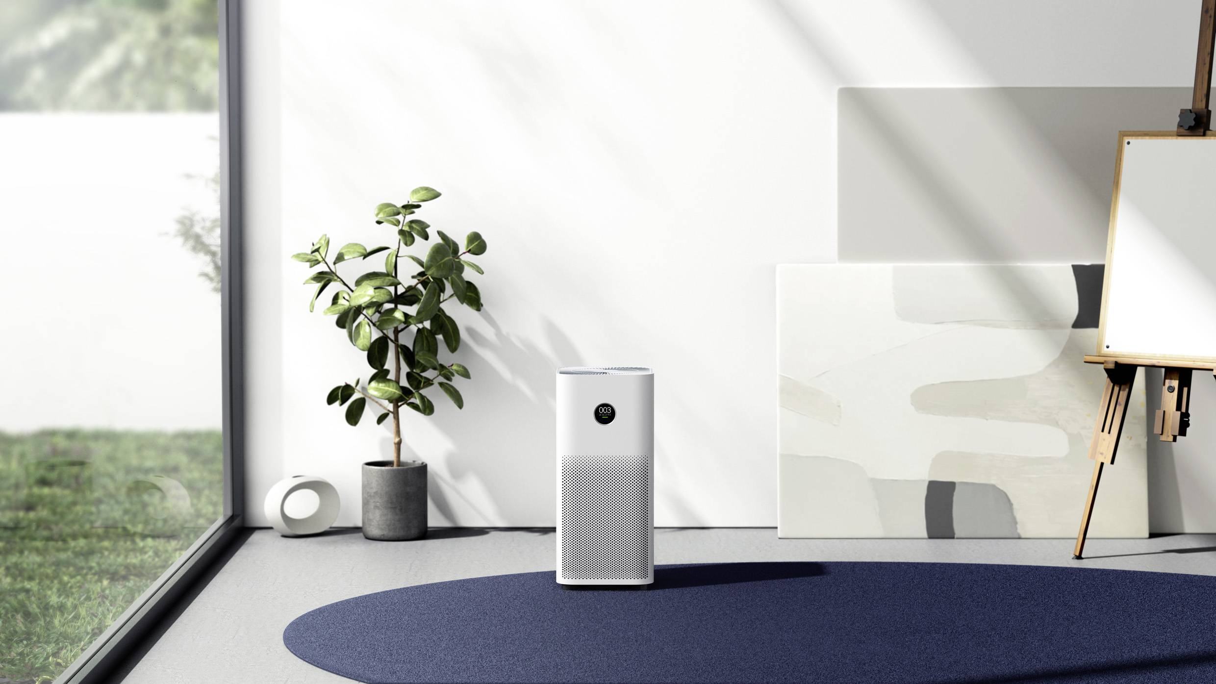 Ein moderner Luftreiniger steht in einem hellen Raum neben einer Pflanze und einer Staffelei mit Leinwand, beleuchtet von Tageslicht.
