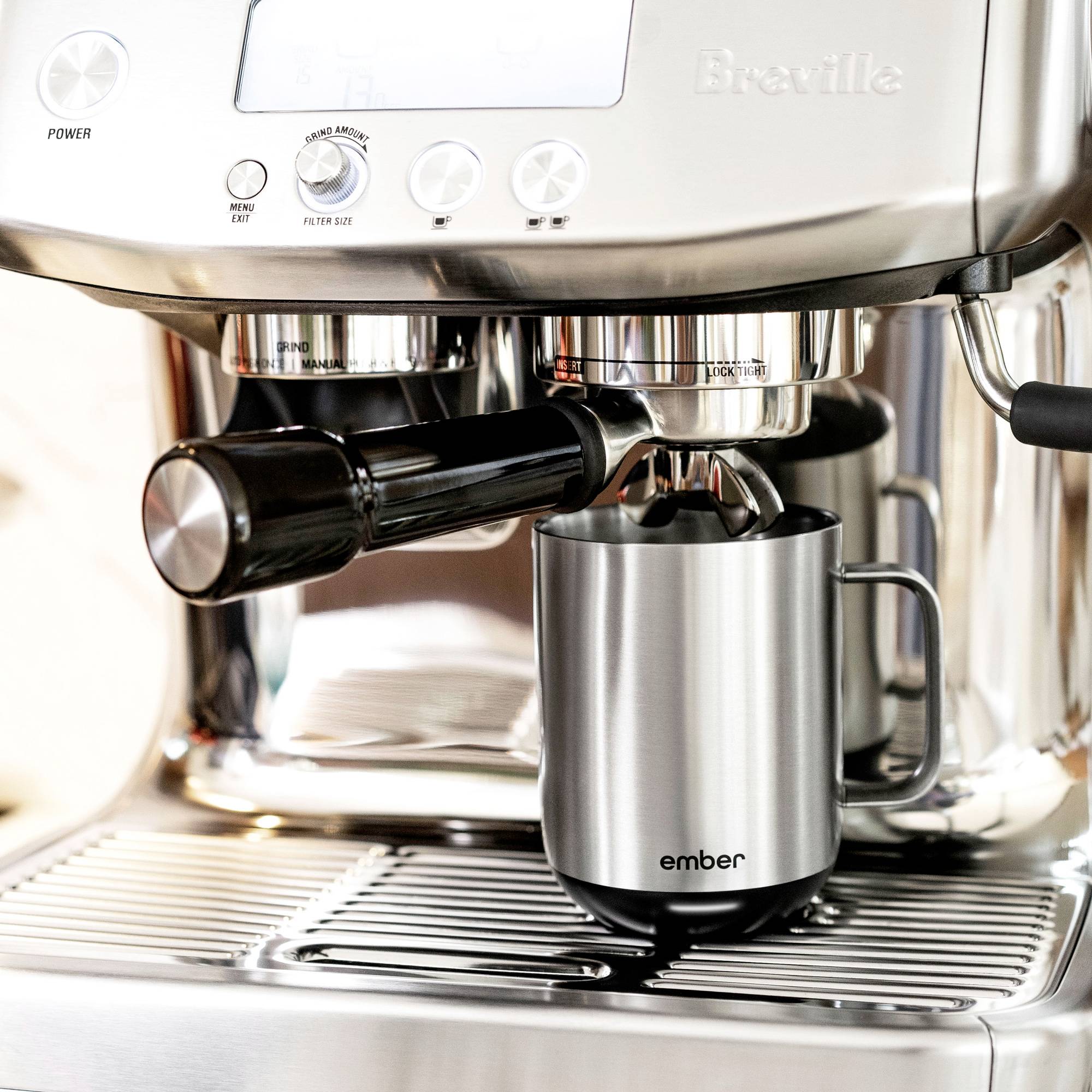 Eine Espressomaschine aus Edelstahl mit einem Arm und einer Tasse darunter.