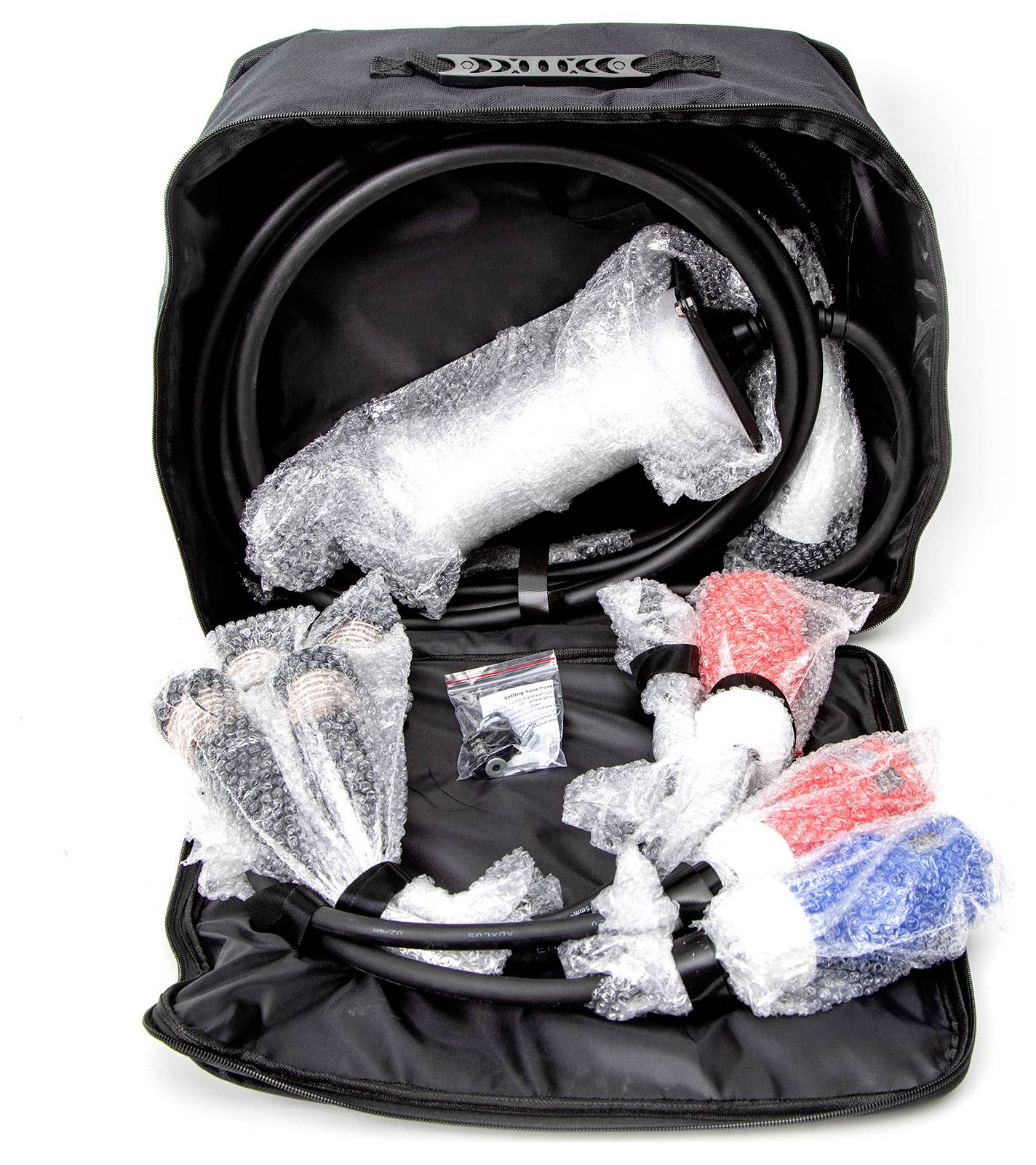 Tragetasche geöffnet mit gepolsterten Kabeln und Verbindungen im Inneren. Verpackungen aus Luftpolsterfolie schützen die Teile.