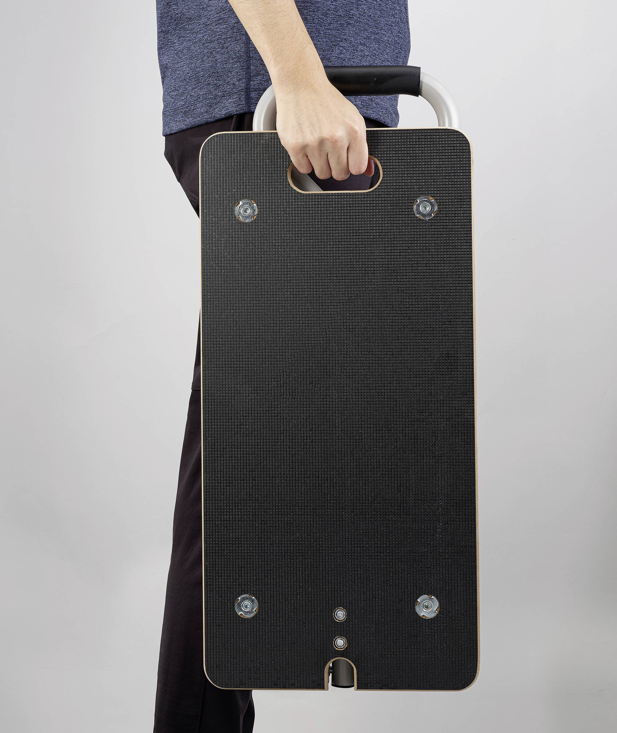 Eine Person trägt ein rechteckiges schwarzes Balance-Board mit einer Hand am Griff.