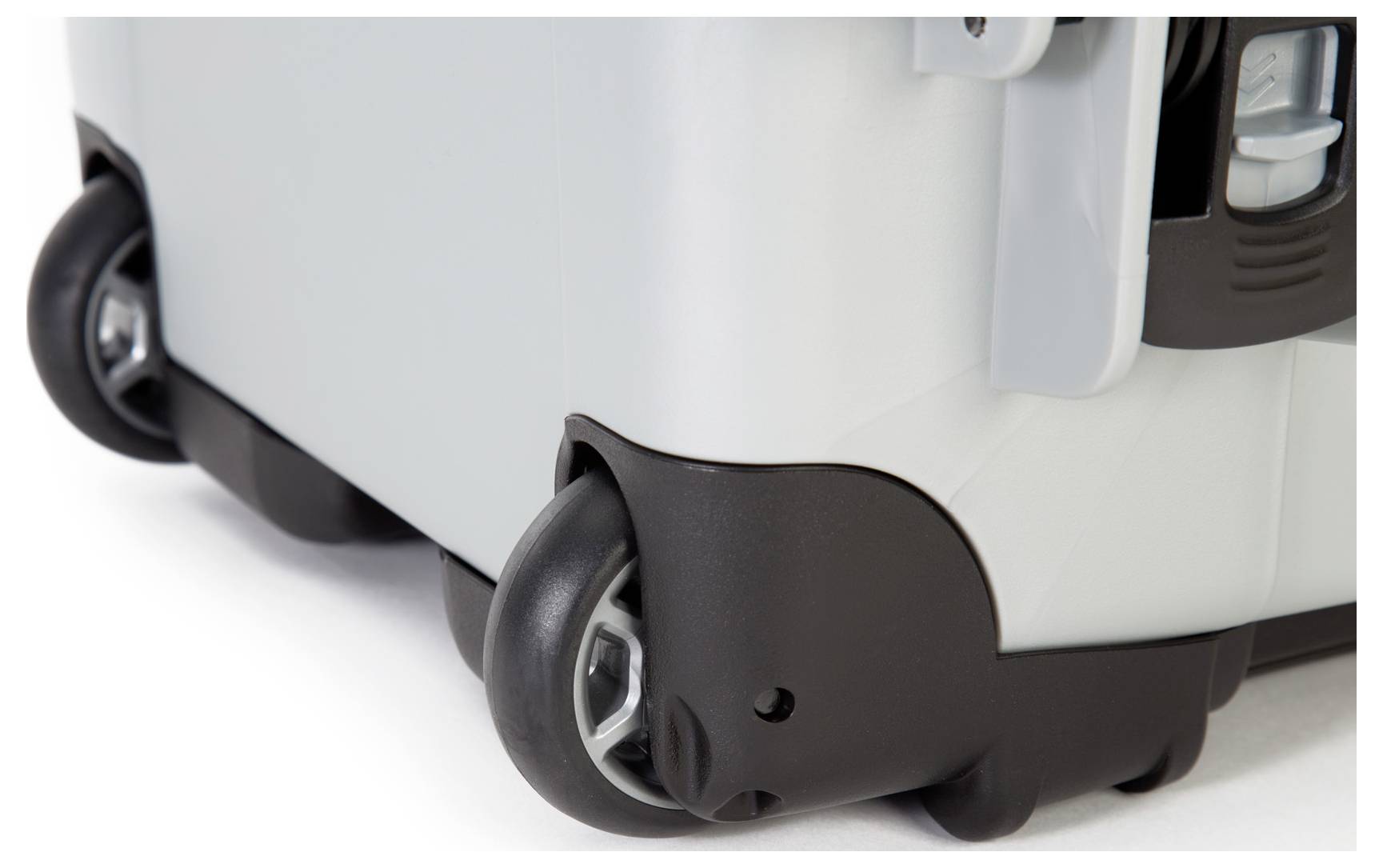 Close-up eines grauen Koffers mit schwarzen Kunststoffrollen und robusten Ecken.