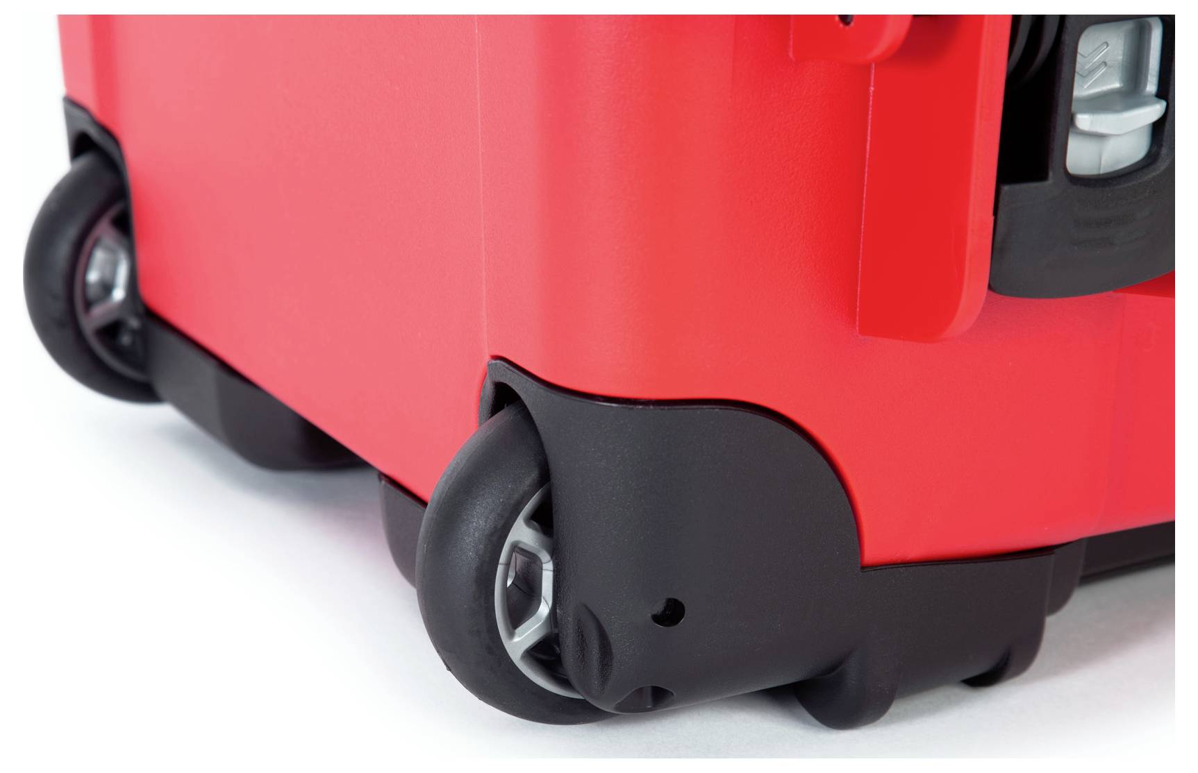 Roter Koffer mit schwarzen Rädern, gezeigt in Nahaufnahme.