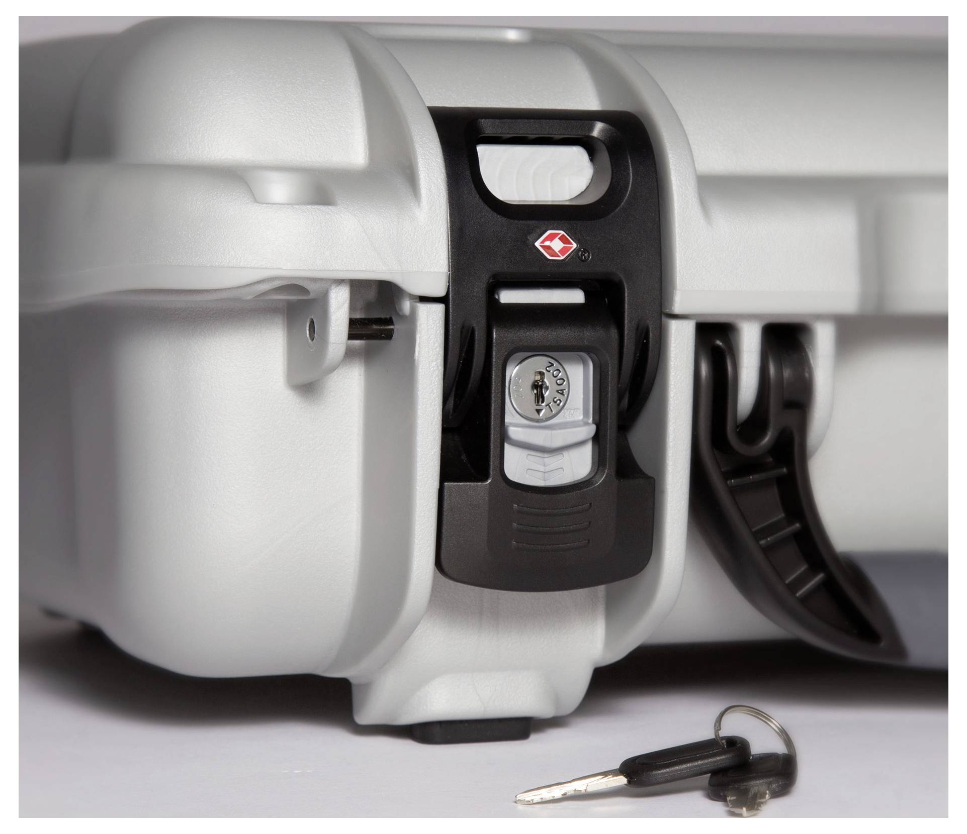 Silberner Sicherheitskoffer mit Zahlenschloss, steht auf einer Fläche. Daneben liegt ein Schlüssel mit schwarzem Griff.