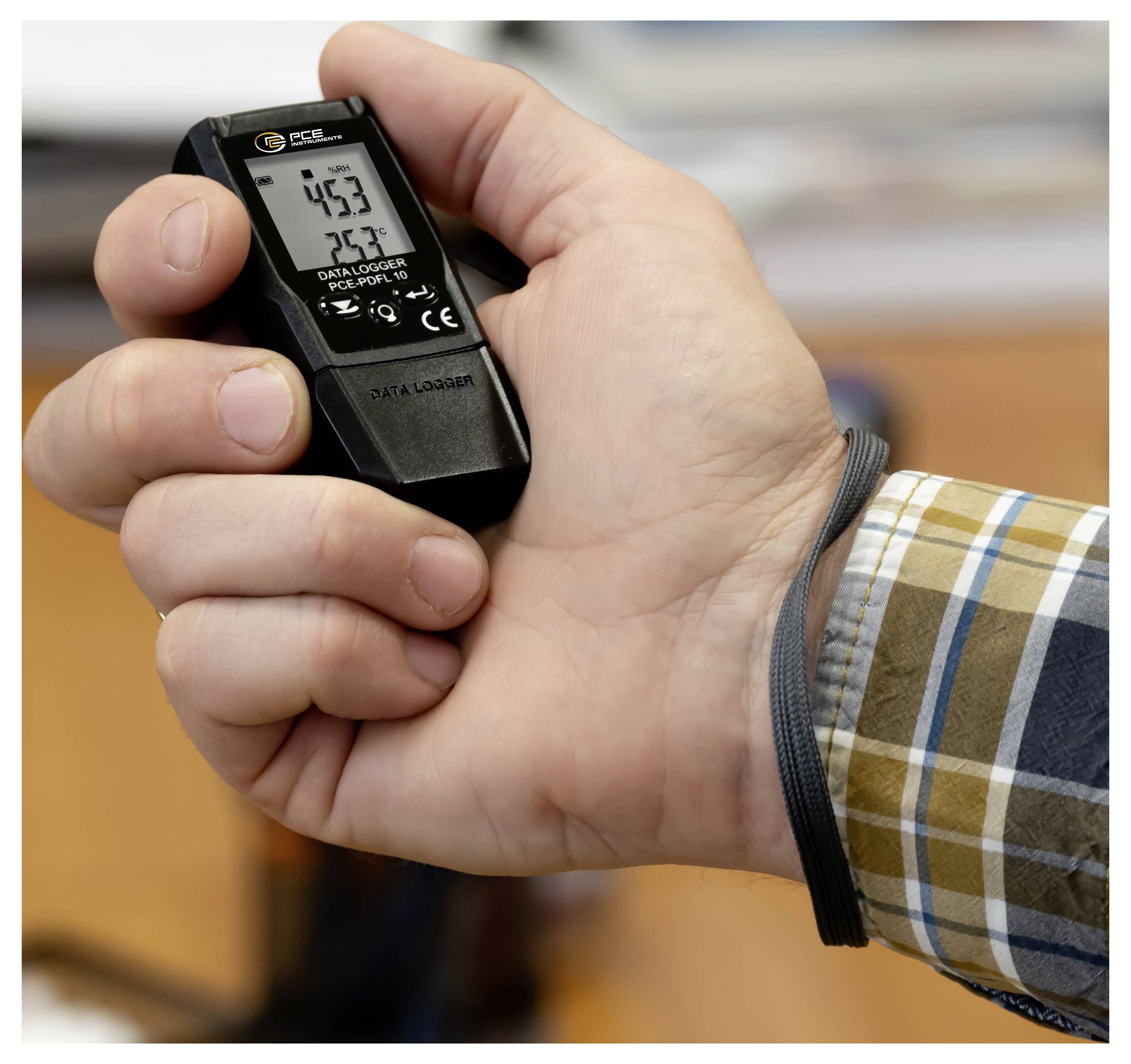 Hand, die einen kleinen digitalen Datenlogger mit einem Bildschirm hält, auf dem die Messwerte „4,53