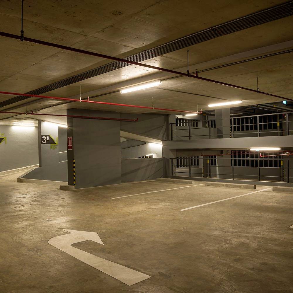 Ein leerer, beleuchteter Innenparkplatz mit Pfeilen, die die Fahrtrichtung anzeigen. An den Wänden sind Stockwerksmarkierungen sichtbar.