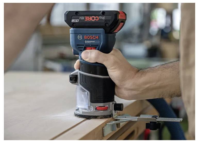 Eine Person bedient einen Bosch Akku-Oberfräser auf einer Holzoberfläche und konzentriert sich dabei auf präzises Holzarbeiten mit einer eingeklemmten Kante als Führung.