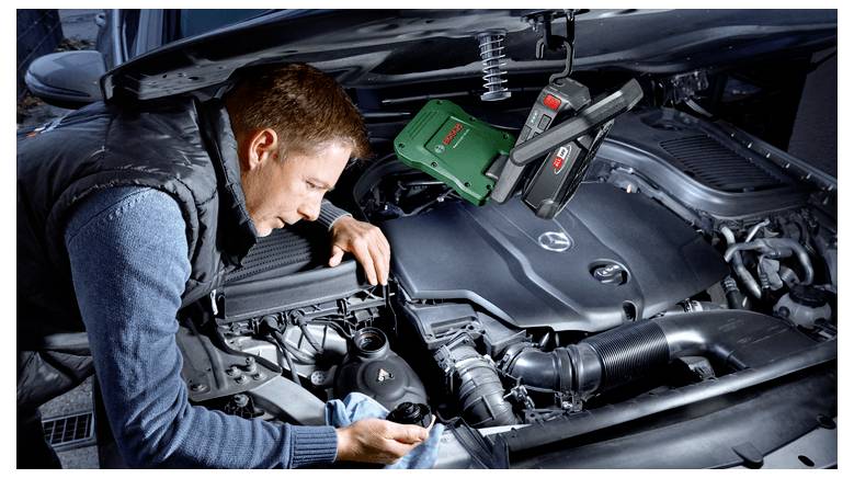 Mechaniker inspiziert einen Automotor unter offener Motorhaube und verwendet ein Diagnosegerät unter der Haube.