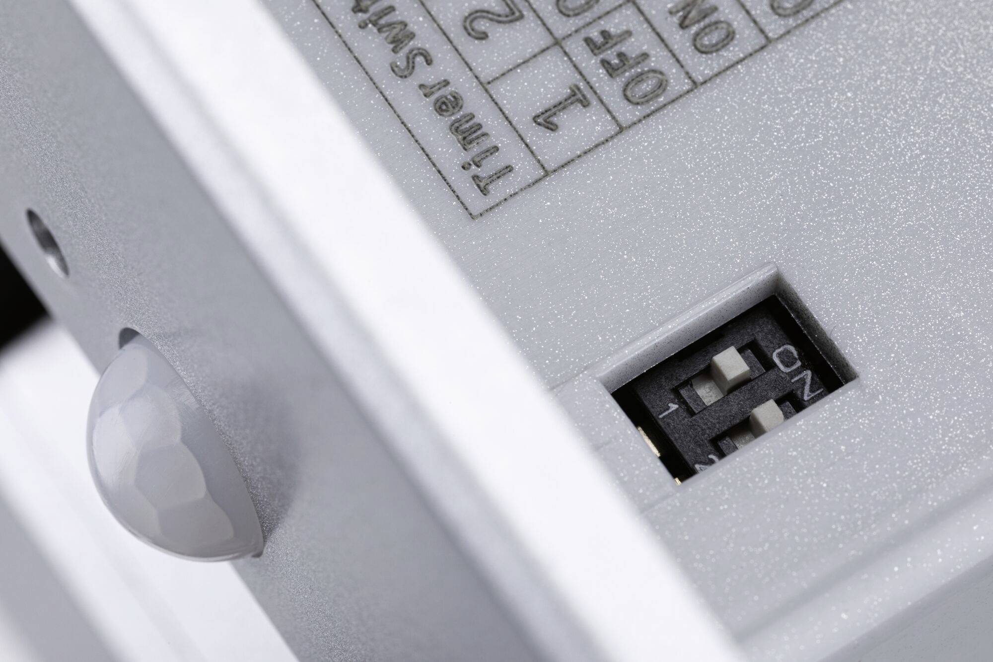 Nahaufnahme eines elektrischen Schalters mit einem Bewegungssensor und einem kleinen Schalter mit drei Einstellungen.