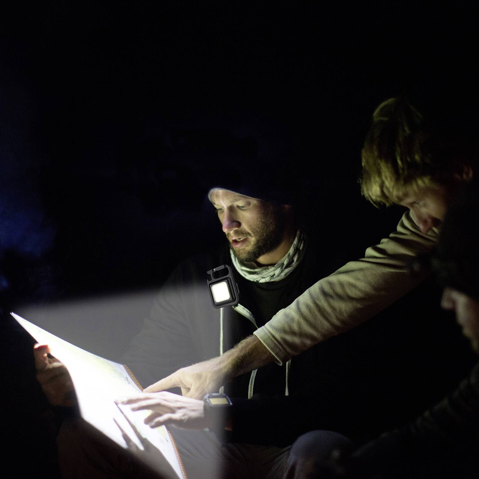 Eine Gruppe von Personen liest bei schwachem Licht ein Dokument. Eine Person zeigt mit der Hand auf das Papier, um etwas zu erklären.