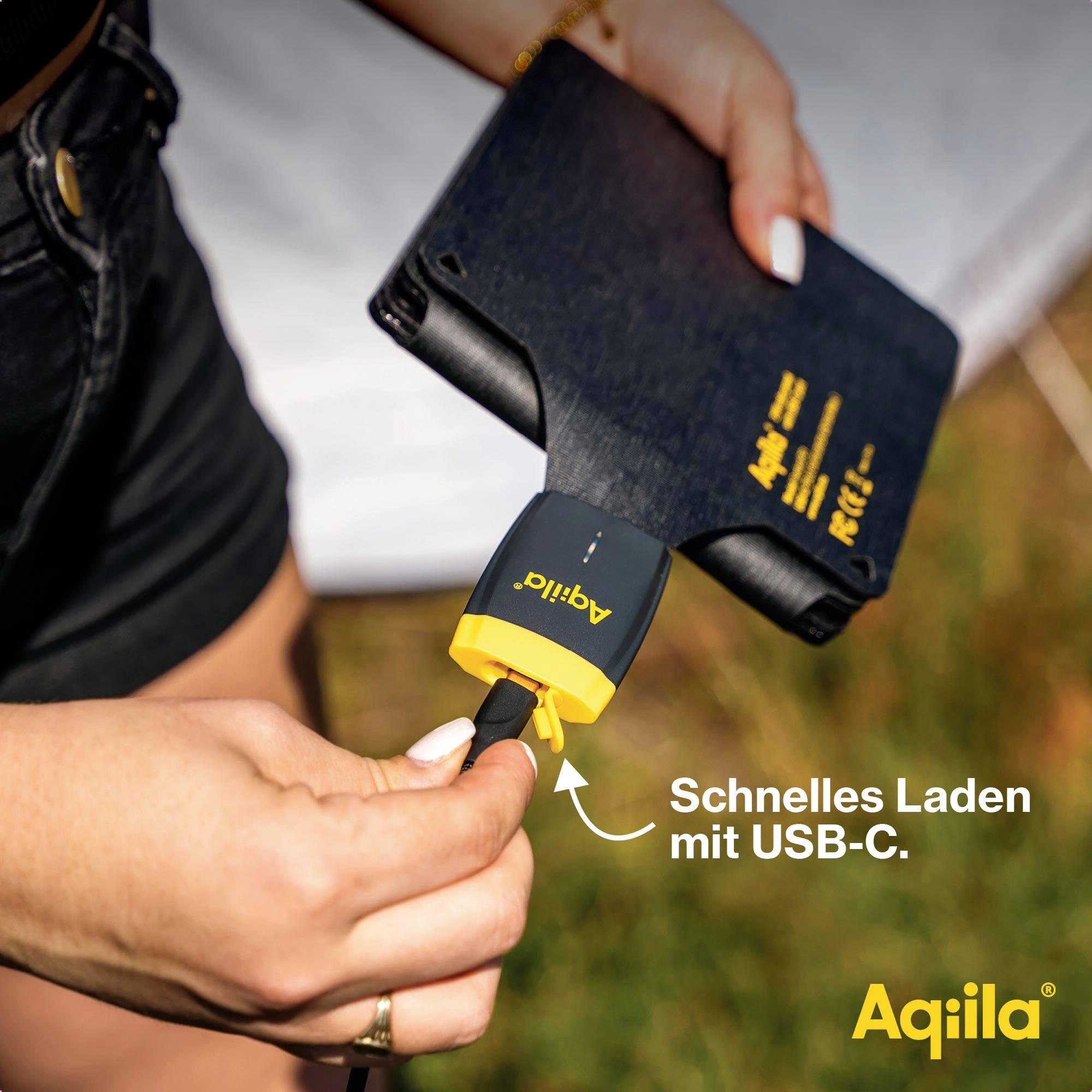 Eine Person hält ein Tablet und schließt ein Kabel an. Text auf dem Bild: 'Schnelles Laden mit USB-C.' Marke unten rechts.