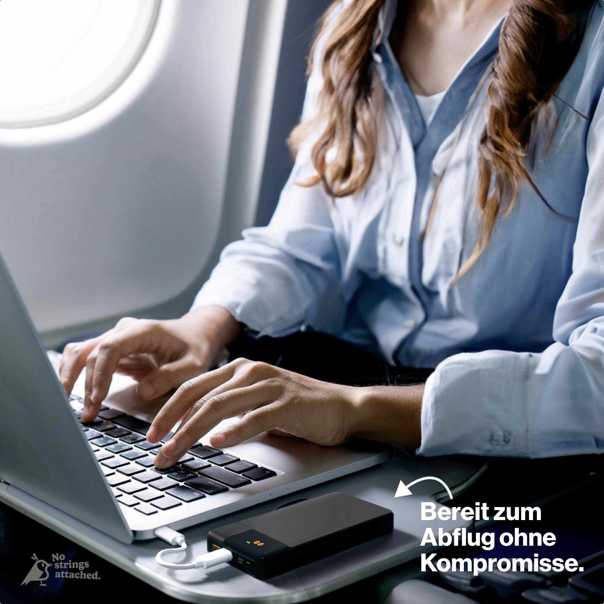 Eine Person tippt auf einem Laptop im Flugzeug. Ein Smartphone lädt über eine Powerbank. Text: 'Bereit zum Abflug ohne Kompromisse.'