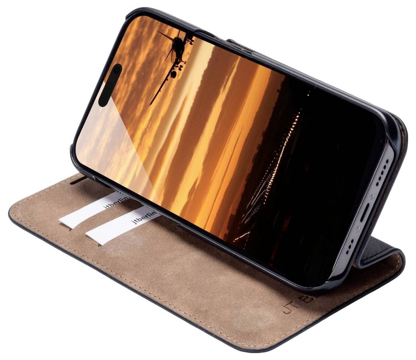 Smartphone in einer braunen Hülle, aufgestellt in einem horizontalen Winkel. Der Bildschirm zeigt einen Sonnenuntergang mit Flugzeug.