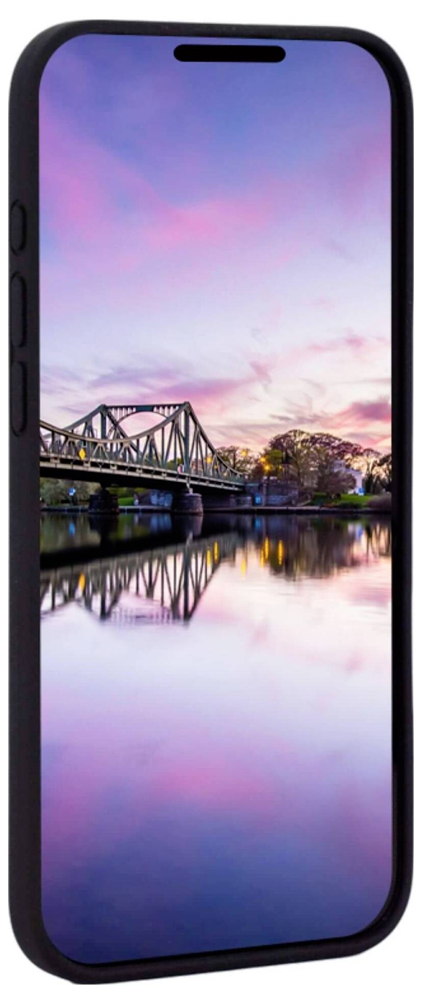 Ein Smartphone zeigt ein Foto von einer Brücke bei Sonnenuntergang, reflektiert im ruhigen Wasser darunter, vor einem rosa Himmel.