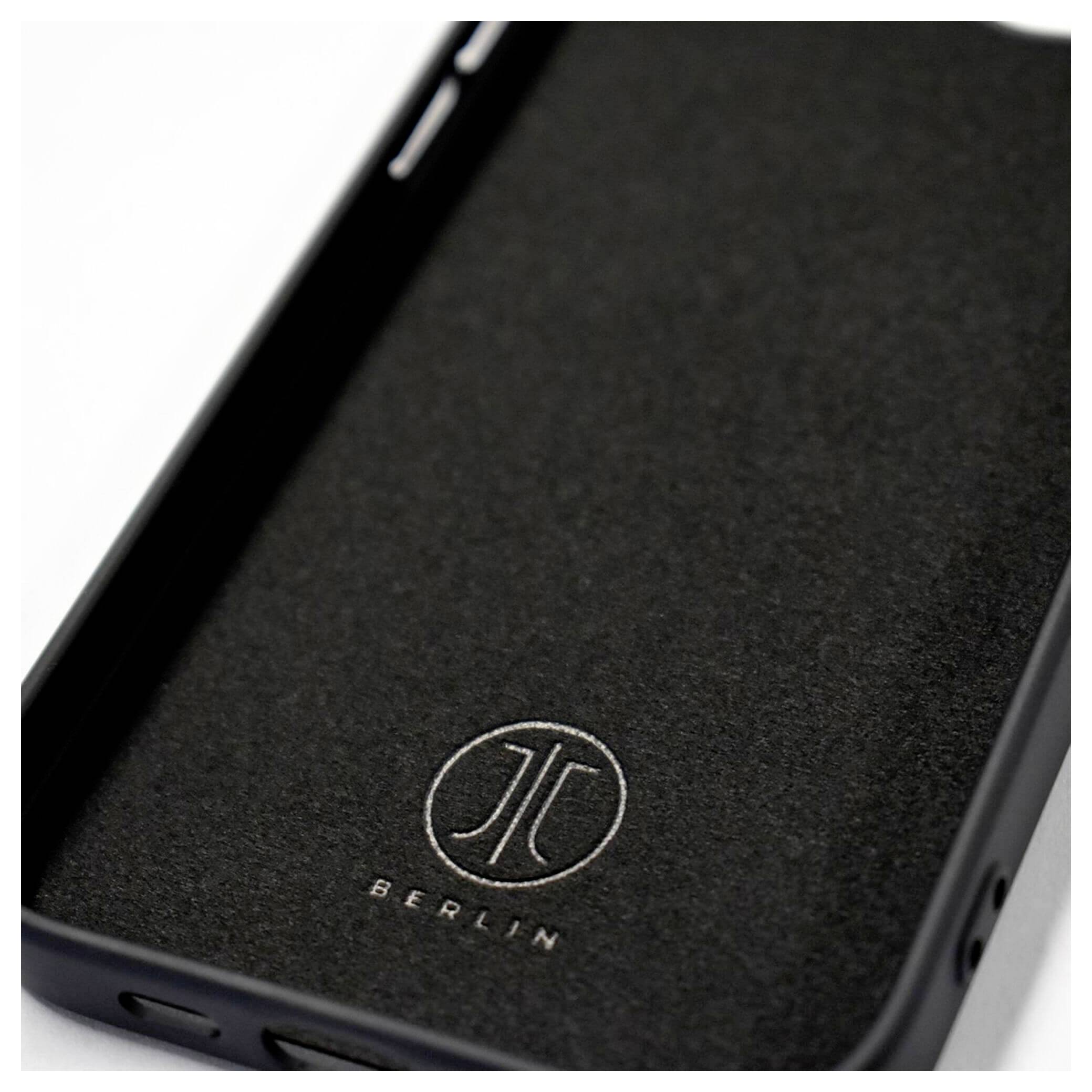 Ein schwarzes Smartphone-Case mit einem weißen Logo und dem Schriftzug 'BERLIN'. Die Hülle liegt flach und füllt den Bildrahmen.