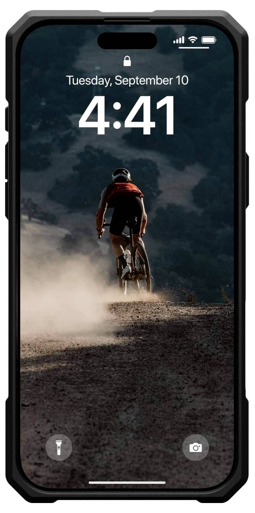 Ein Radfahrer in Sportkleidung fährt auf einem staubigen Weg bergauf, umgeben von Bäumen. Auf dem Handybildschirm wird die Uhrzeit 4:41 angezeigt.