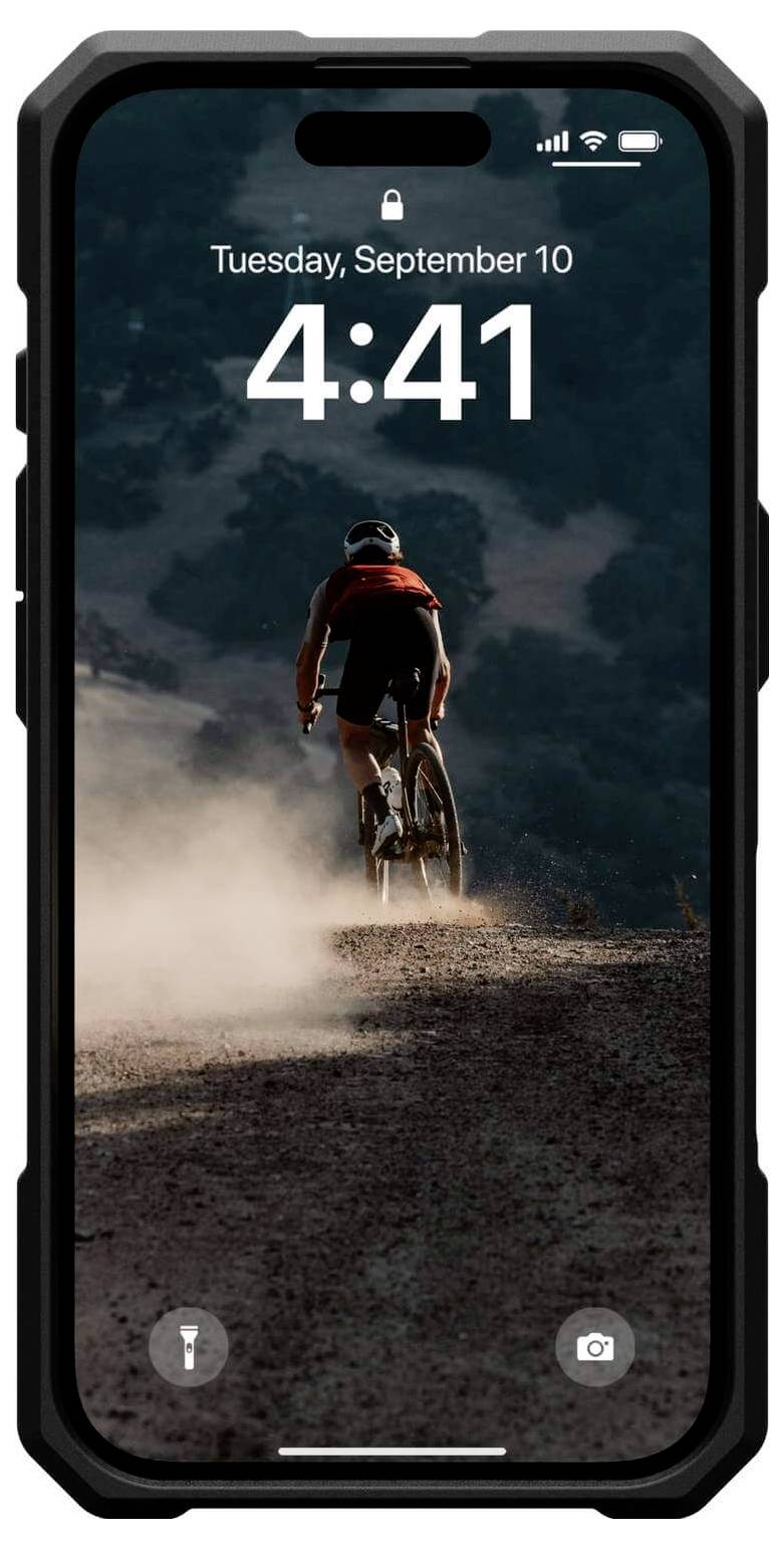 Ein Fahrradfahrer fährt auf einem staubigen Weg im Abendlicht bergauf. Im Hintergrund bewaldete Hügel. Oben ist die Uhrzeit 4:41 angezeigt.