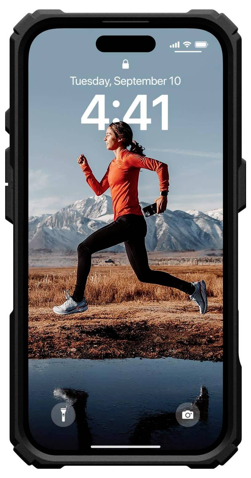 Eine Frau joggt im Freien neben Bergen, während sie ein Smartphone in der Hand hält. Datum und Uhrzeit in der Anzeige sichtbar.