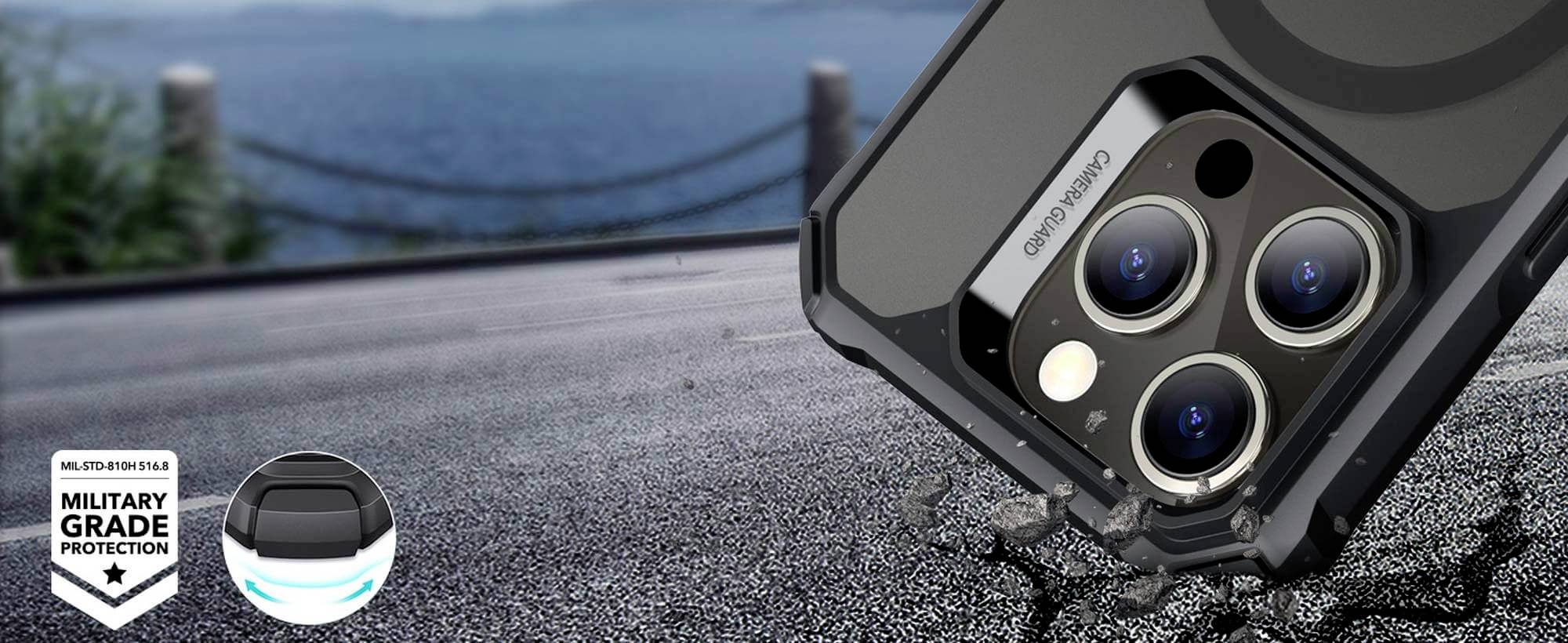 Close-up eines Smartphones mit robuster Hülle auf Asphalt, Fokus auf die Kamera. Text: 'MILITARY GRADE PROTECTION'. Hintergrund zeigt Meer.