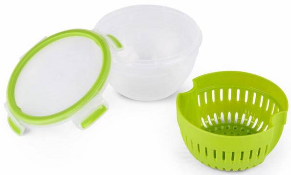 Eine grüne Abtropfschüssel und ein transparenter Deckel liegen neben einer weißen Schüssel auf einer weißen Fläche.