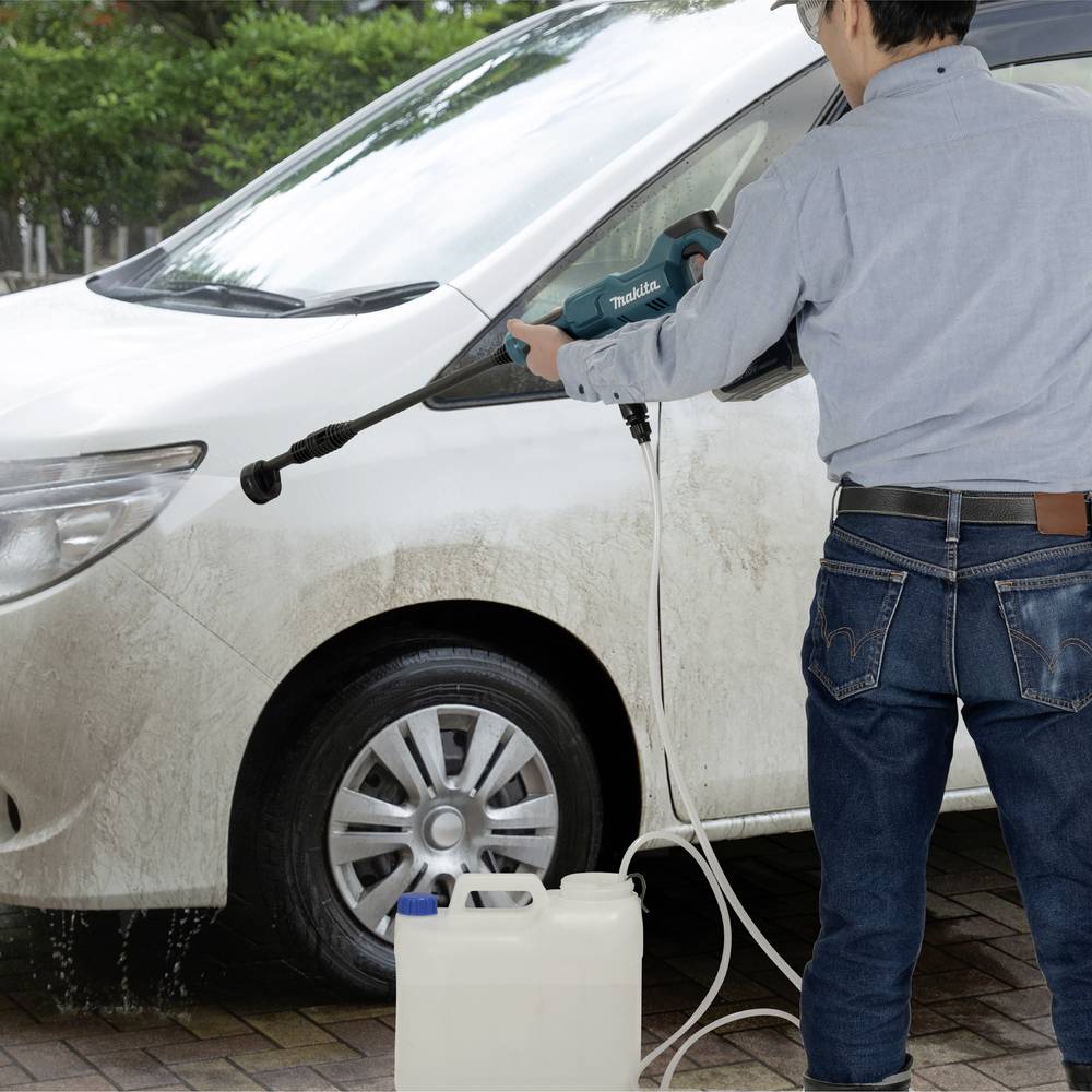 Eine Person reinigt ein weißes Auto mit einem Hochdruckreiniger im Freien. Ein Kanister mit Reinigungsmittel steht daneben.