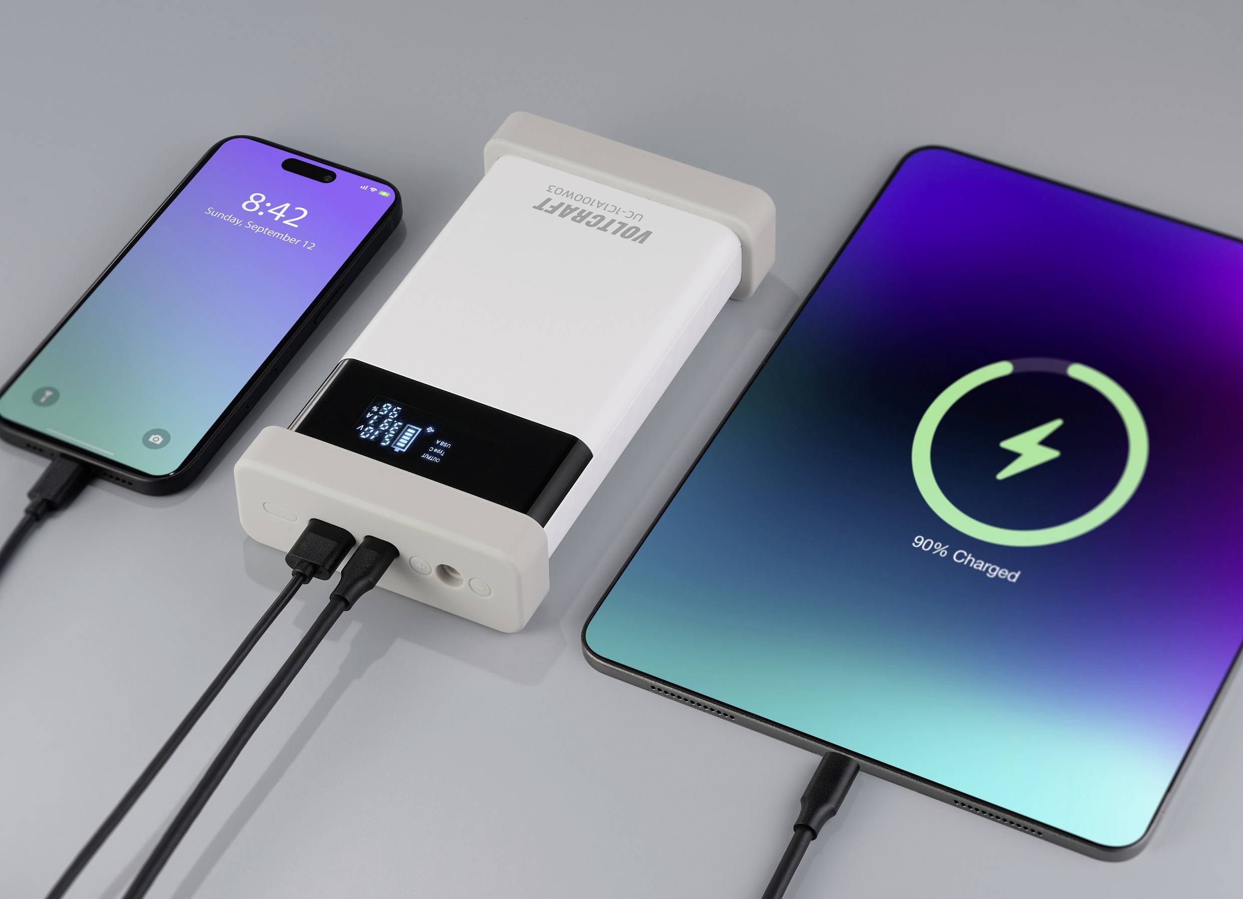 Ein Smartphone und ein Tablet werden mit einem tragbaren Ladegerät aufgeladen. Das Smartphone zeigt die Uhrzeit '8:42', das Tablet ist zu 90% geladen.