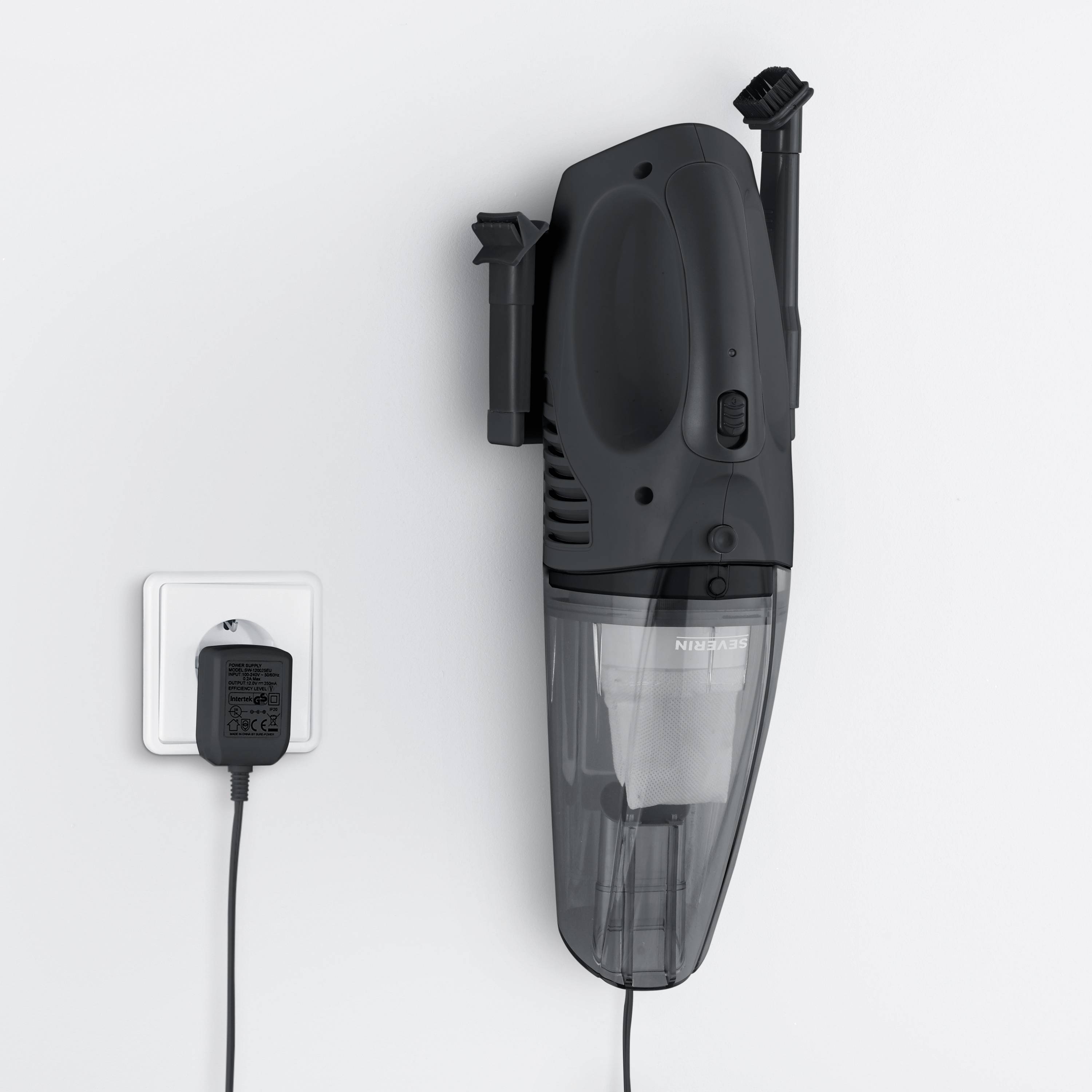 Ein kabelloser Handstaubsauger hängt an einer Wandladestation. Das Ladegerät ist an eine Steckdose angeschlossen.