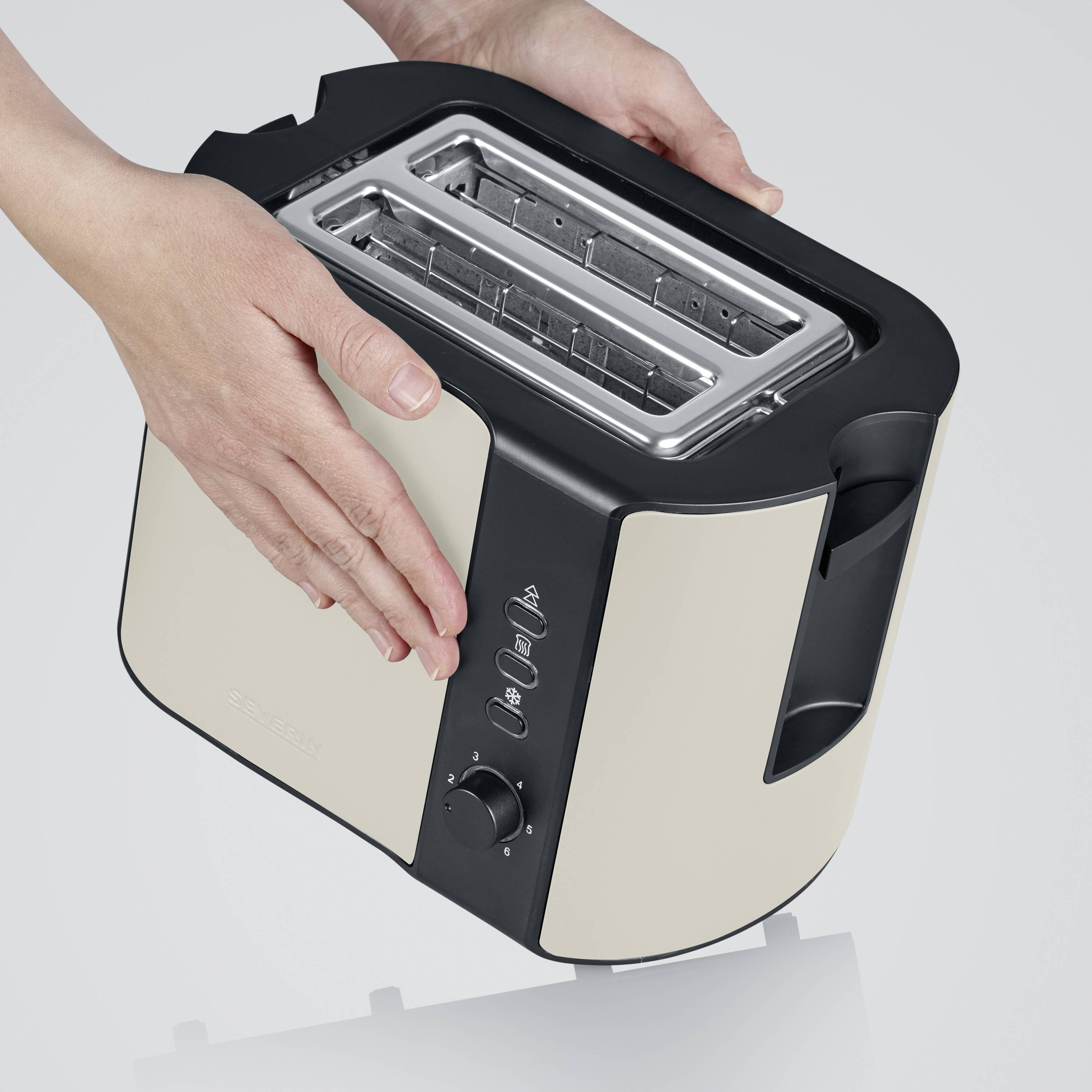 Ein silber- und schwarzfarbener Toaster mit zwei Schlitzen wird von einer Hand gehalten. Bedienelemente sind vorne sichtbar.
