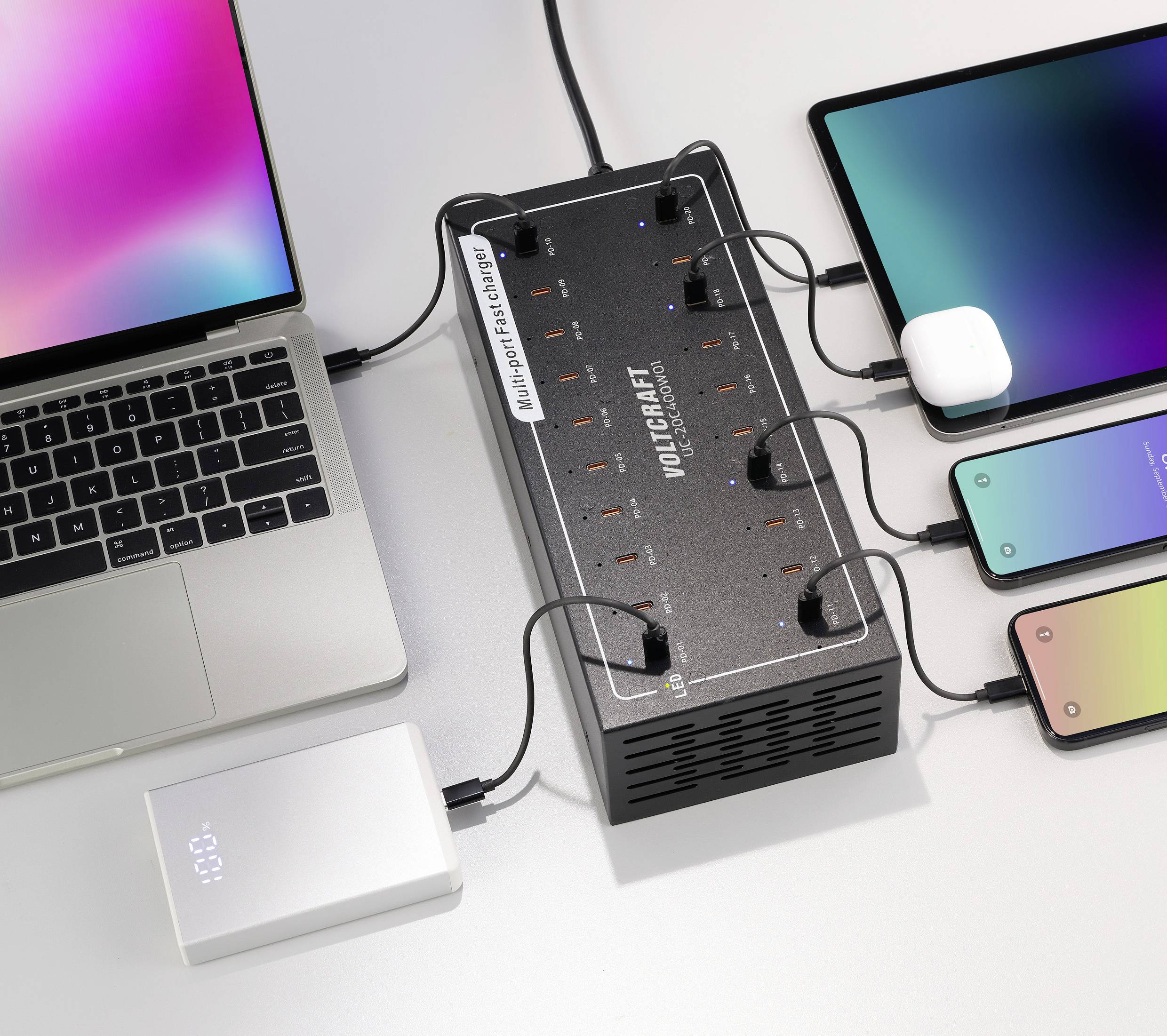 Ein Mehrfach-USB-Ladegerät lädt gleichzeitig ein Laptop, ein Tablet und zwei Smartphones. Ein weiteres Gerät ist daneben angeschlossen.