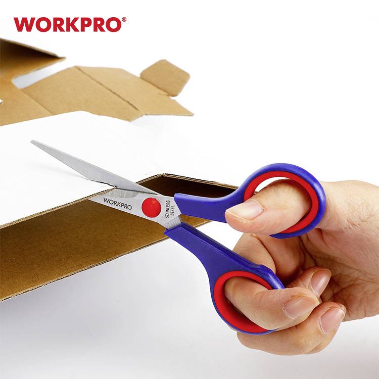 Eine Hand hält eine blaue und rote Schere und schneidet Pappe. Im Hintergrund ein Karton mit dem Text 'WORKPRO'.