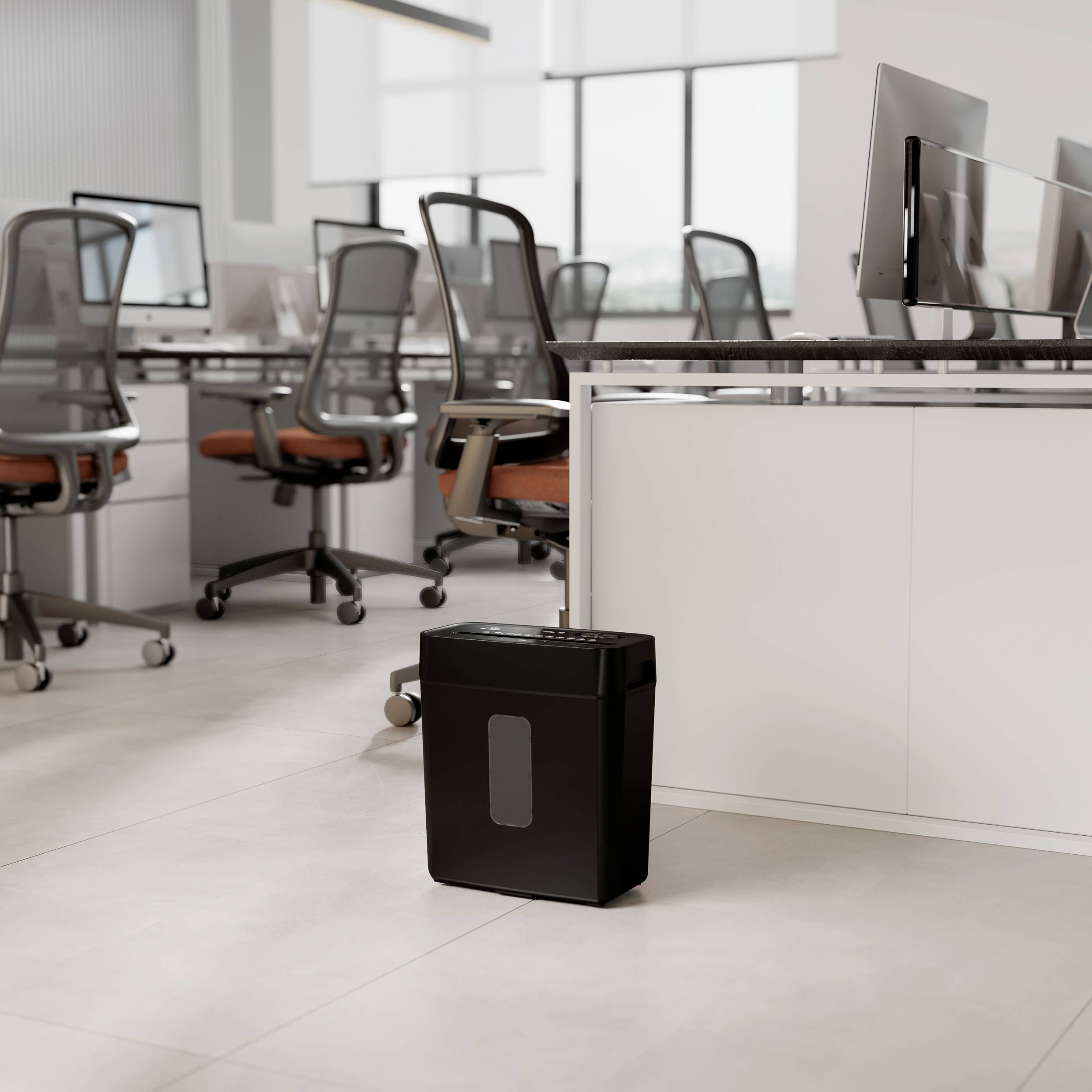 Ein Büro mit mehreren Schreibtischen und Computern; im Vordergrund steht ein schwarzer Aktenvernichter auf dem Boden.