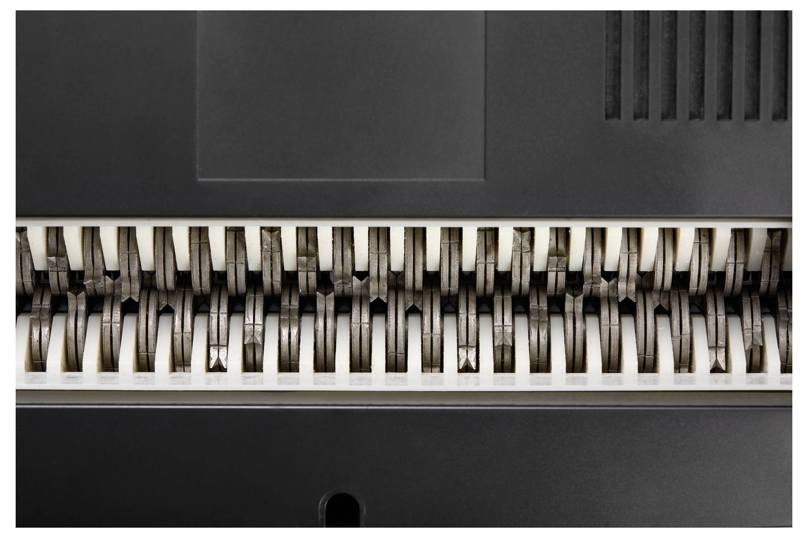 Nahaufnahme eines Papierschredders mit rotierenden Klingen, die zum Zerkleinern von Papierdokumenten verwendet werden.