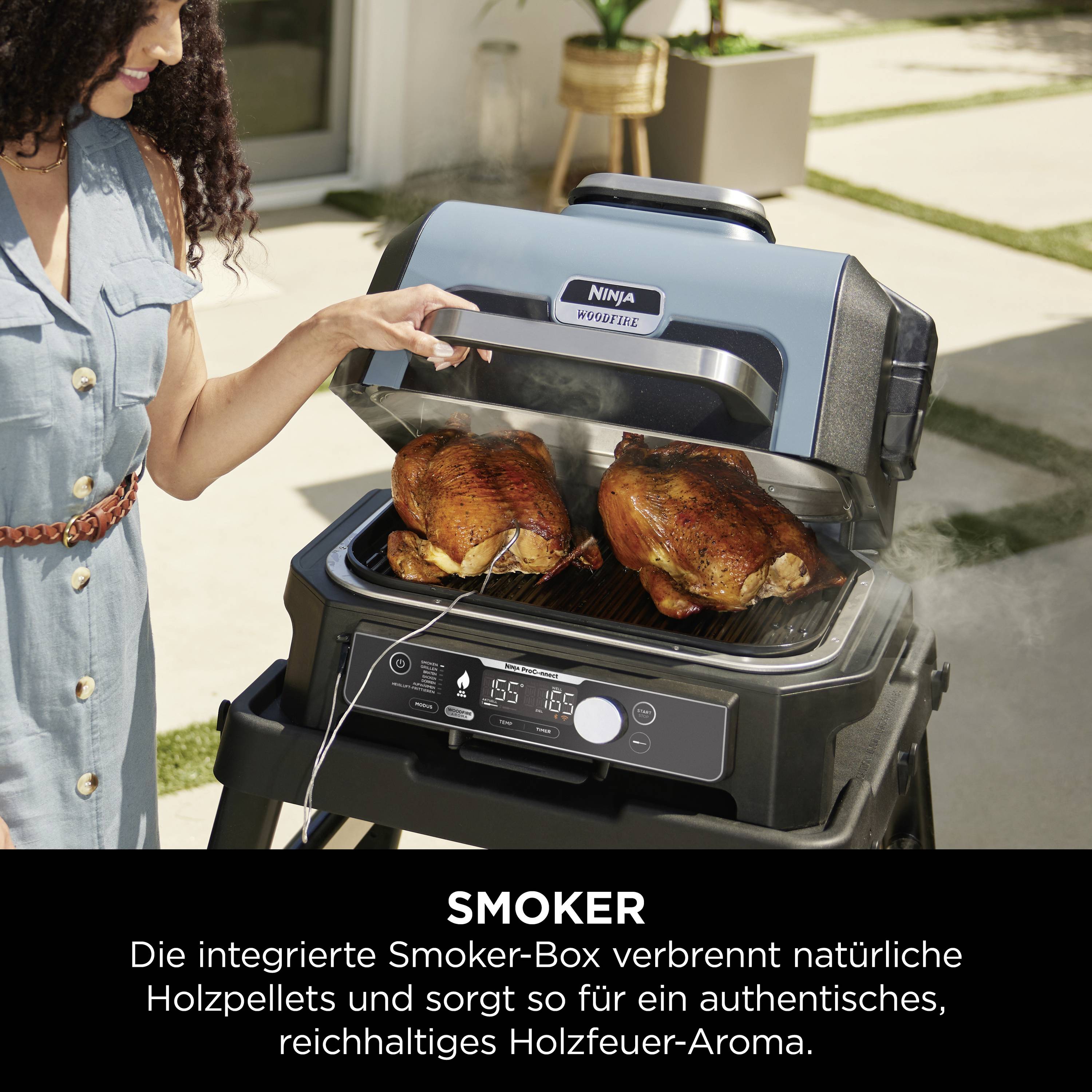 Eine Frau steht neben einem Smoker-Grill, der zwei gegrillte Hähnchen enthält. Text erklärt die Holzaromafunktion des Smokers.